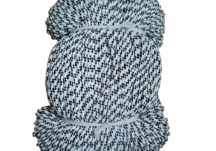 A roll of black and white patterned twine or cord, wrapped and tied with a white string, placed on a wooden surface.