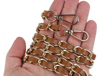 Brown leather chain with gold metal clasp held in a hand on a white background