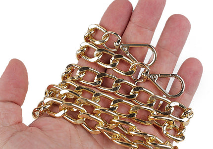 Gold chain held in a hand against a white background