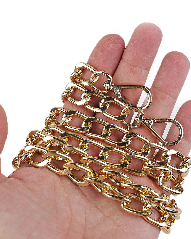 Gold chain held in a hand against a white background