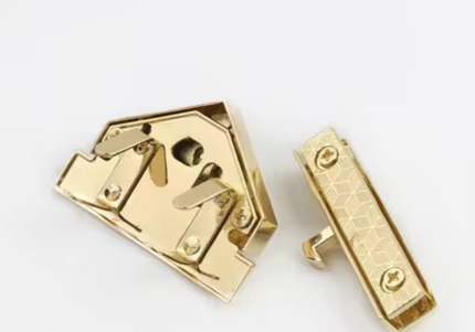 Back view of the gold triangle turn lock clasp showing screw holes and locking mechanism parts.
